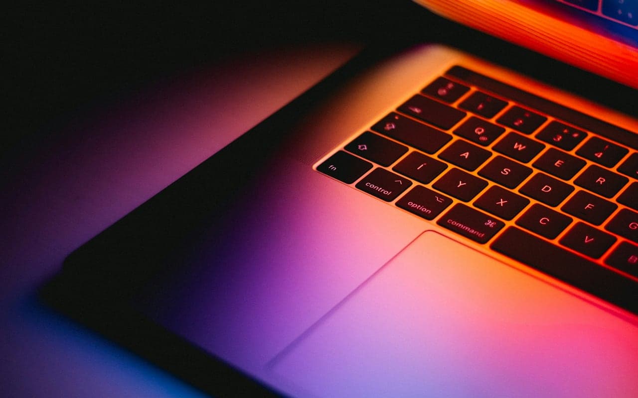 Laptop keyboard lit by colored light representing connected software systems